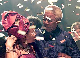 Former South African President Nelson Mandela and his wife Graca Machel celebrate underneath a shower of confetti at a glamourous multi-racial banquet