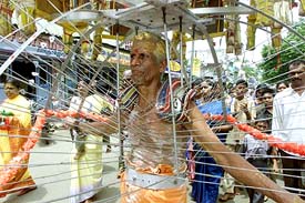A man with his body pierced by sharp objects marches in a religious celebration