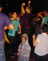 A child adorns a raincoat as his parents dance during a rain dance organised at a local resorts