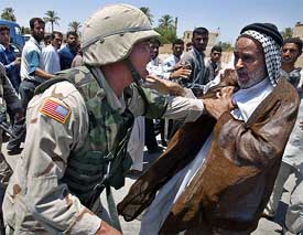 A US soldier pushes an Iraqi man during a demonstration in Kerbala