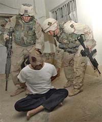 US soldiers take a man into custody during a morning raid at a house in Tikrit
