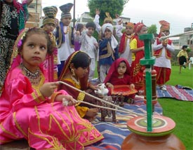 A child from Kiddies Paradise churns milk on the occasion of the Teej celebrations