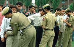 Policemen frisk Kashmiri people during a search operation in Srinagar