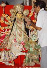 Amarandra Nath Ghosh, a Kumartuli artist, gives final touches to a Durga idol