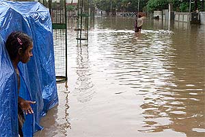 A girl peers out of her tent, flooded by rain waters