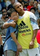 Real Madrid's Brazilian defender Roberto Carlos hugs an orphan whose parents died of SARS