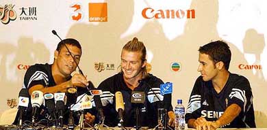 Real Madrid star Ronaldo gives the microphone to his new teammate David Beckham as Raul Gonzalez looks on