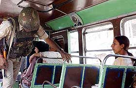 Security force personnel search a bus in Srinagar on Sunday.