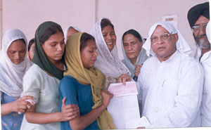 Mandi Board Chairman Sant Ram Singla presents a cheque for Rs 1 lakh to the mother of a boy, who was killed by a policeman recently