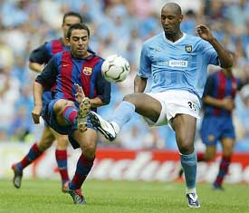 Barcelona's Xavier Hernandez fights for the ball with Nicolas Anelka of Manchester City