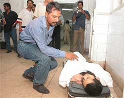 A doctor examines a body, killed in a shooting incident, at a Karachi hospital