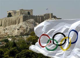 An Olympic flag blows in the wind in front of the Acropolis hill