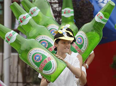 Chinese participants wave inflatable Tsingtao beer bottles during a parade 