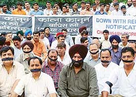 Traders wearing black bands sit in dharna against the Rent Act notification in Chandigarh on Friday.