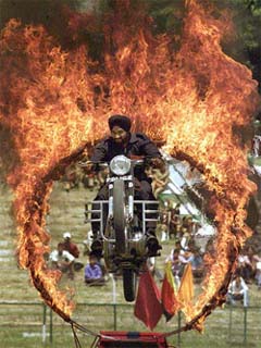 A Kashmir Police motorcyclist jumps through a ring of fire