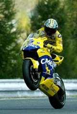 Italy's Max Biaggi performs a wheelstand on his Honda after winning the first qualifying practice race