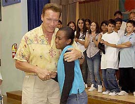 Actor Arnold Schwarzenegger hugs Jodaiah Love as he greets schoolchildren