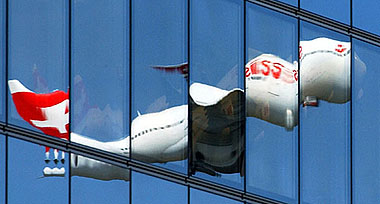 A Swiss Air Lines aircraft is reflected on the windows of a building at Zurich airport 
