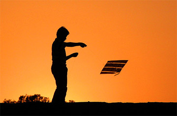 A boy flies a kite as the sun sets in Jammu