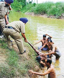 A policeman and divers retrieve the body of Gajram, who drowned in the rivulet of Sukhna Lake, near the regulator end, in Chandigarh