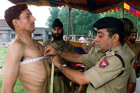 A police officer measures chest of a youth for recruitment