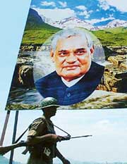 A CRPF soldier walks past the billboard with the picture of the Prime Minister in Srinagar on Tuesday.