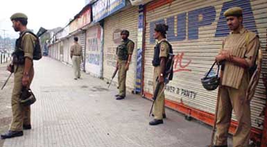 Security personnel patrol a deserted street in Srinagar 