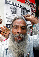A protester raises slogans in front of a poster showing Saudi dissident Osama Bin Laden and former Union Carbide chairman Warren Anderson 
