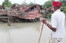 An old man looks helplessly at his hut,  destroyed due to heavy rain at Abhasing Pura village near Ahmedabad