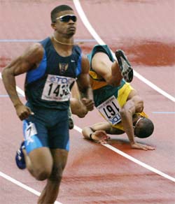 Marcio Simao De Souza of Brazil falls as Terrence Trammell of the US coasts home at the end of the men's 110m hurdles semifinal 