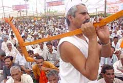 A farmer carries a plough at a rally against the WTO