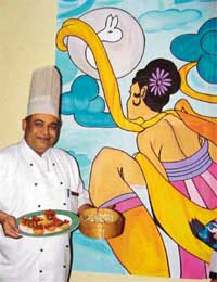 Chef Sudanhshu presents Chinese dishes at the festival of August Moon underway at Orient Blade with the picure of Queen in the back ground