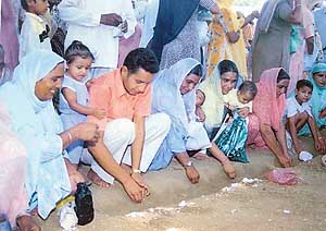 Women scoop the earth from Gugga Marhi.