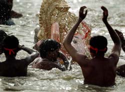 Devotees splash water on a large clay statue of Ganesh during its immersion into the Arabian Sea in Mumbai