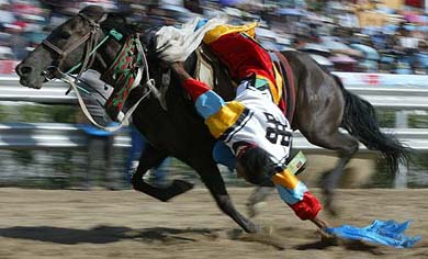 Chinese rider picks up silk scarves as he performs at the horse riding event of the 7th National Ethnic Sports meet
