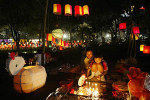 A mother helps her son put up lanterns to mark the Moon Festival at Hong Kong's Victoria Park 