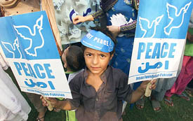 A boy holds placards at a peace rally in Lahore