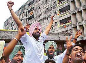 Malwinder Singh Kang raises his hands to acknowledge victory 