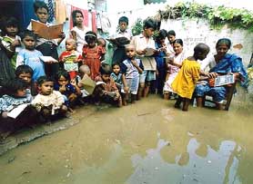 Schoolchildren listen to a teacher at a flooded primary school