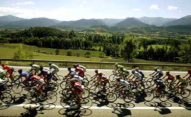 Cyclists ride past the Pyrinees mountains at the 194km 10th stage of the Tour of Spain cycling race in Sabadell, Spain