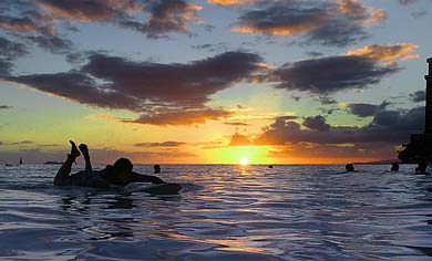 A surfer makes his way back to shore after a day of surfing on Waikiki's famous surfing shores near Hawaii 