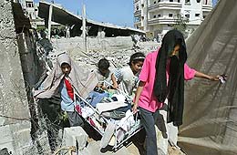 Palestinian girls recover their belongings from their house after it was destroyed during an Israeli raid at Noserat refugee camp in the Gaza Strip