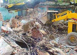 An earth-mover razes illegal kiosks near the main entrance of Mata Mansa Devi shrine during an encroachment drive near Panchkula on Friday.