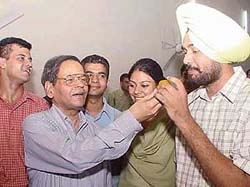 Prof K.N. Pathak, Vice-Chancellor, offers a �ladoo� to Malwinder Singh Kang after he was administered the oath as president of the Panjab University Campus Students Council in Chandigarh on Friday.