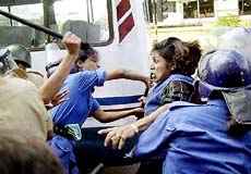 Bangladeshi policewomen use baton and try to arrest an activist of the main opposition Awami League during a nationwide strike in Dhaka
