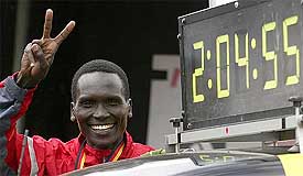 Paul Tergat of Kenya flashes a victory sign next to a clock showing his new world best time after he won the 30th Berlin Marathon 