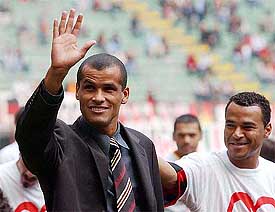 Brazilian soccer star Rivaldo waves to fans as compatriot Cafu looks on 