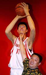 A mainland Chinese tourist poses with the wax figure of NBA player Yao Ming