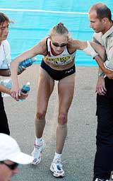 British runner Paula Radcliffe is helped after crossing the finish line