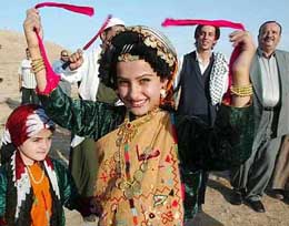 A Kurdish girl, dressed in traditional clothing, dances along with other people